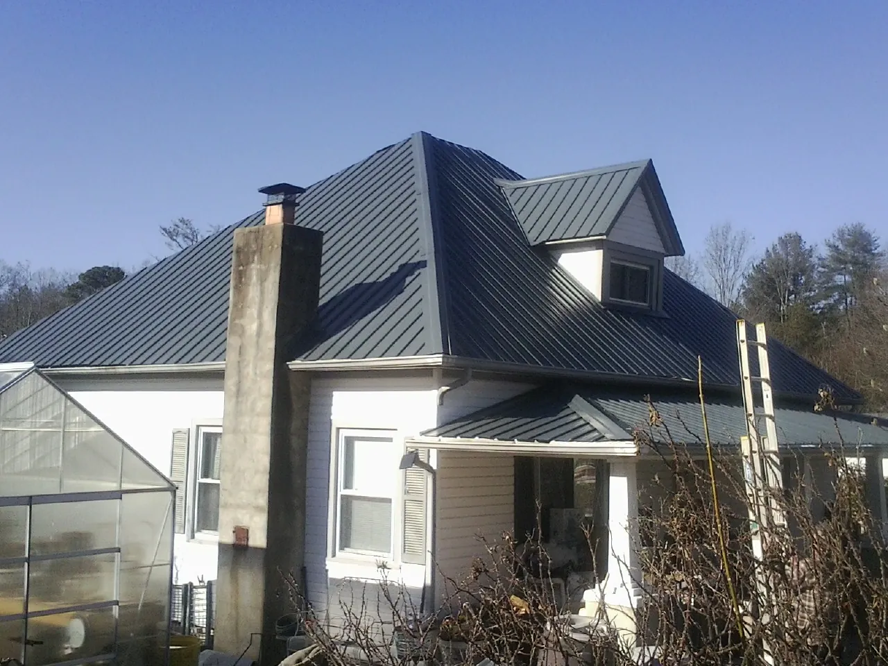 Dark blue standing seam metal roof on a white farmhouse with dormer — Slate & Tile Roof Repair by Roofing Brothers in Encino
