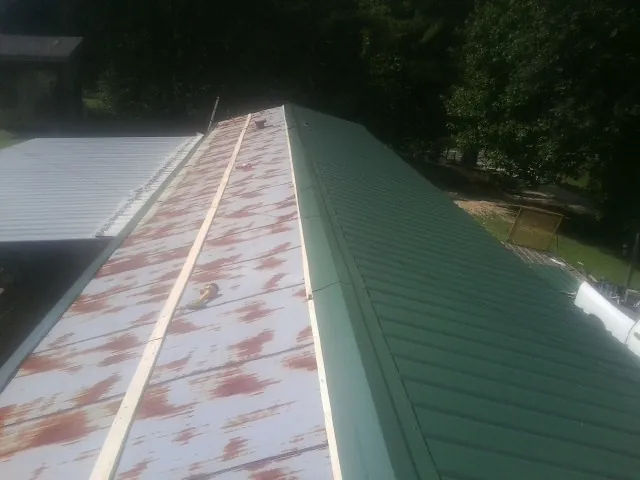 Old rusted panels beside newly installed green metal roofing — Wind Damage Roof Repair by Roofing Brothers in Encino