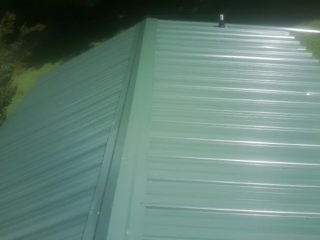 New green metal panels meeting at the ridge of a roof — Flat Roof Repair work by our crew in Encino