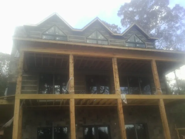 Dormers and porch framing on a large log home under construction — Roof Coating work by our crew in Encino