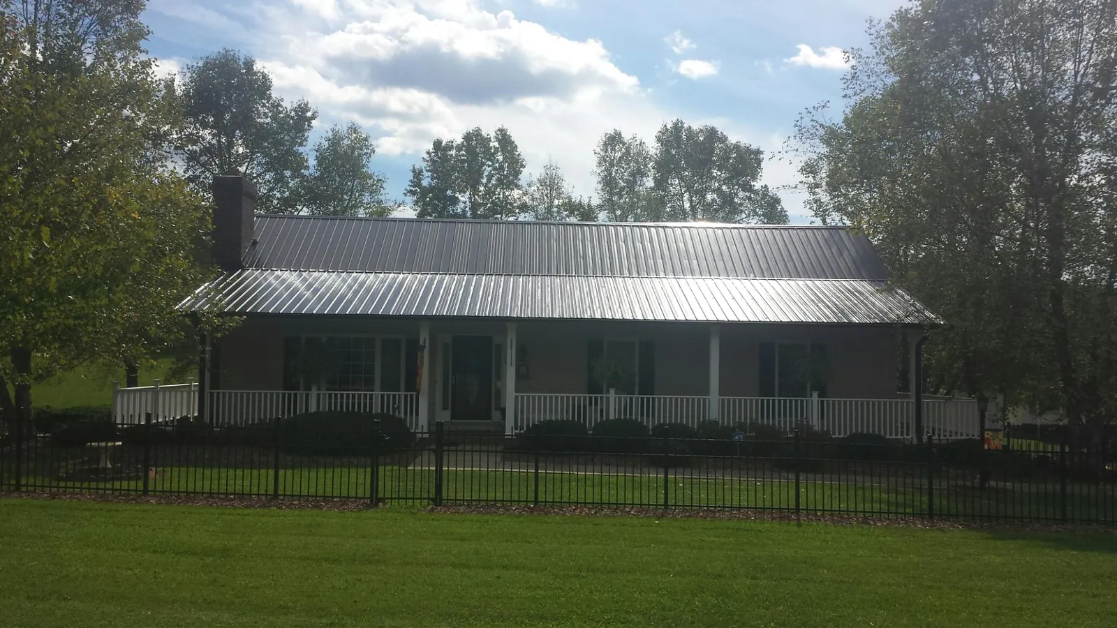 Gray metal roof on a brick ranch with a full width front porch — Gutter Guard Installation work by our crew in Encino