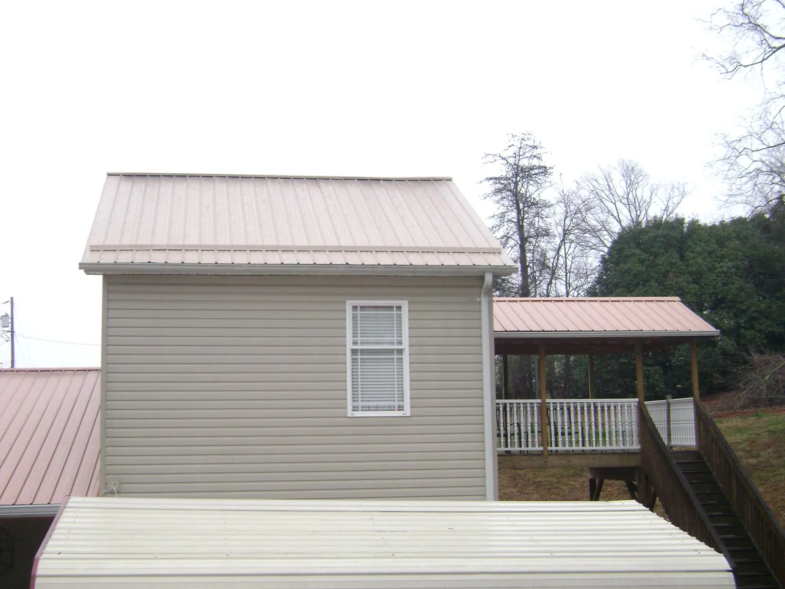 Tan metal roofs on a two story addition and attached porch, from a Roof Replacement job in Encino