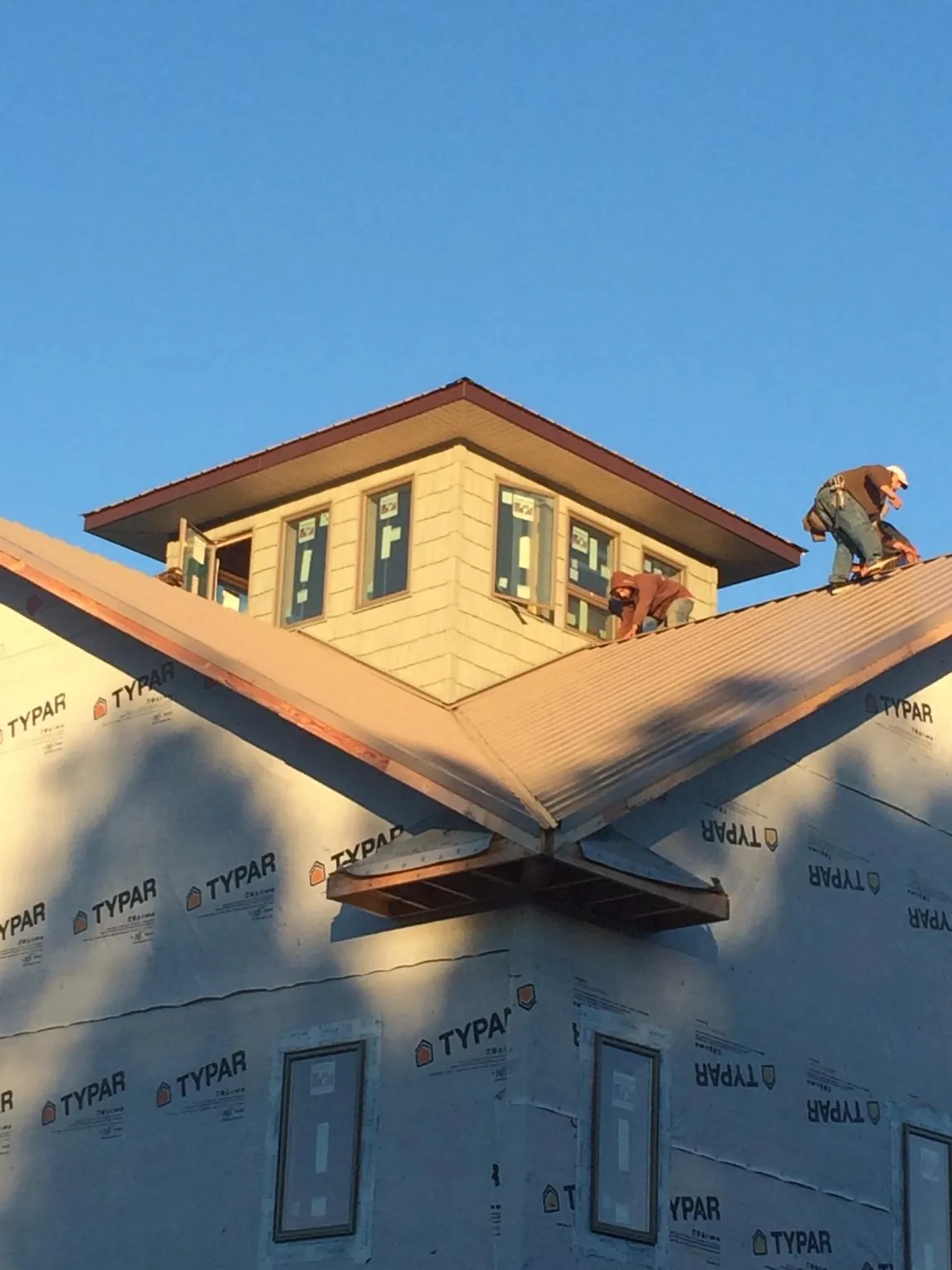Roofers working around a rooftop cupola on a new metal roof at sunset — Roof Waterproofing in Encino by Roofing Brothers